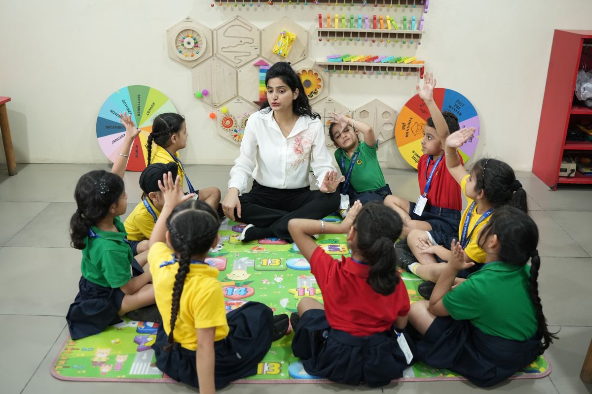 A teacher and young children playing a counting game on a number mat at TSUS Sarabha Nagar