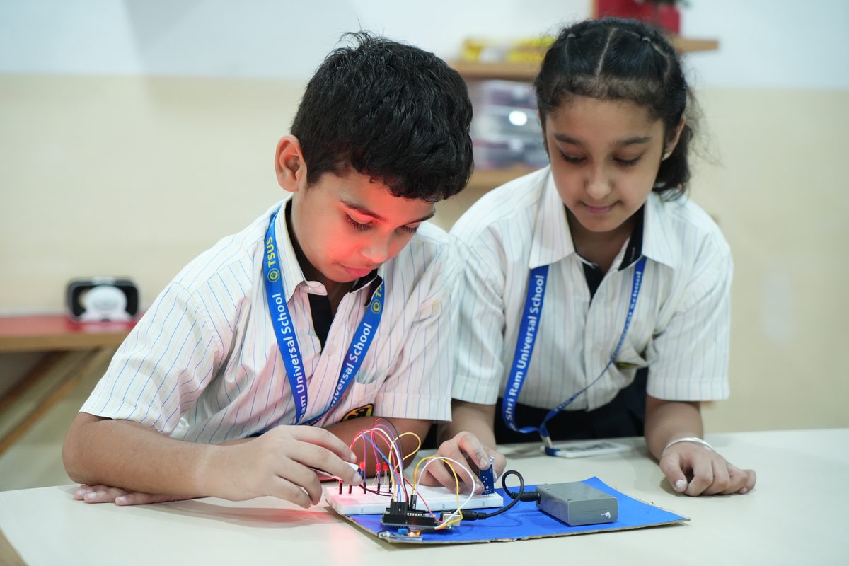 Two students connect wires and components on a circuit board in the STEM Lab at TSUS Sarabha Nagar